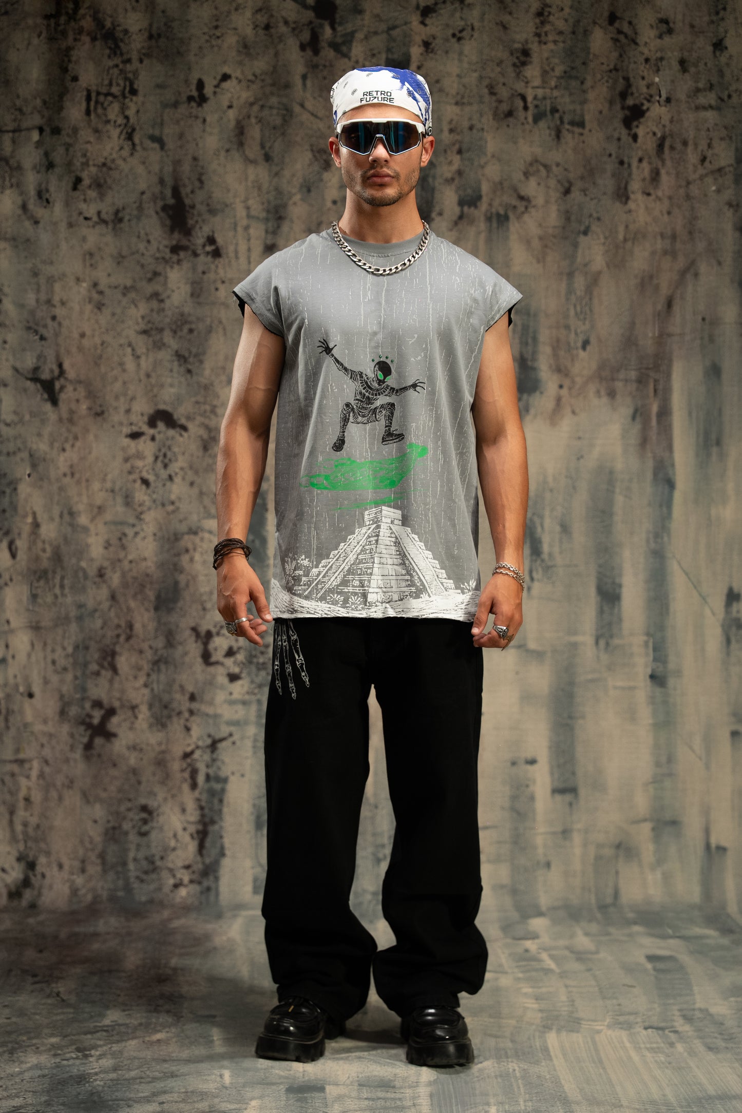 Man wearing a graphic t-shirt and sunglasses against a textured wall.