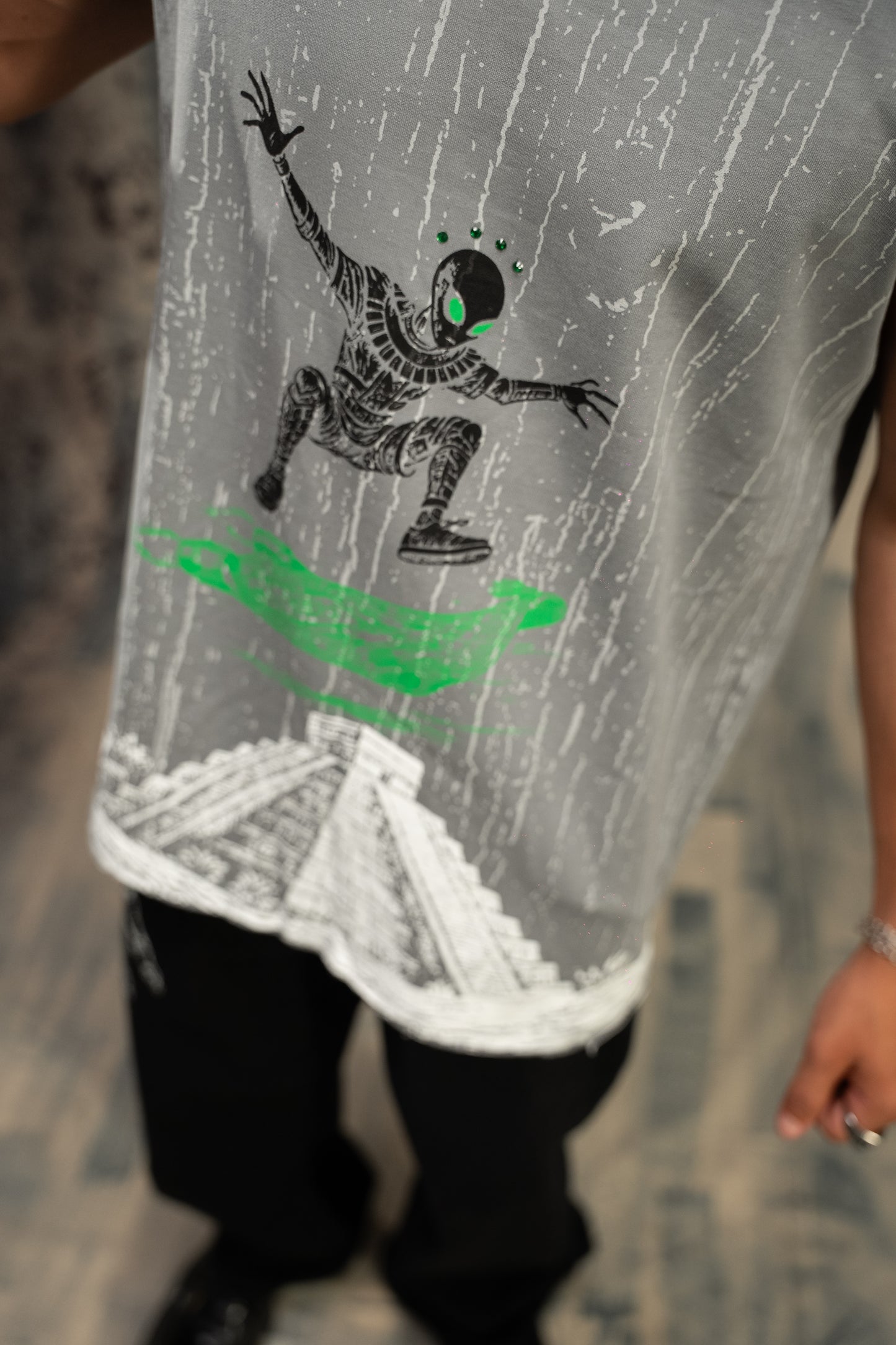Gray sleeveless shirt with a graphic design of a person on a surfboard in green and black.