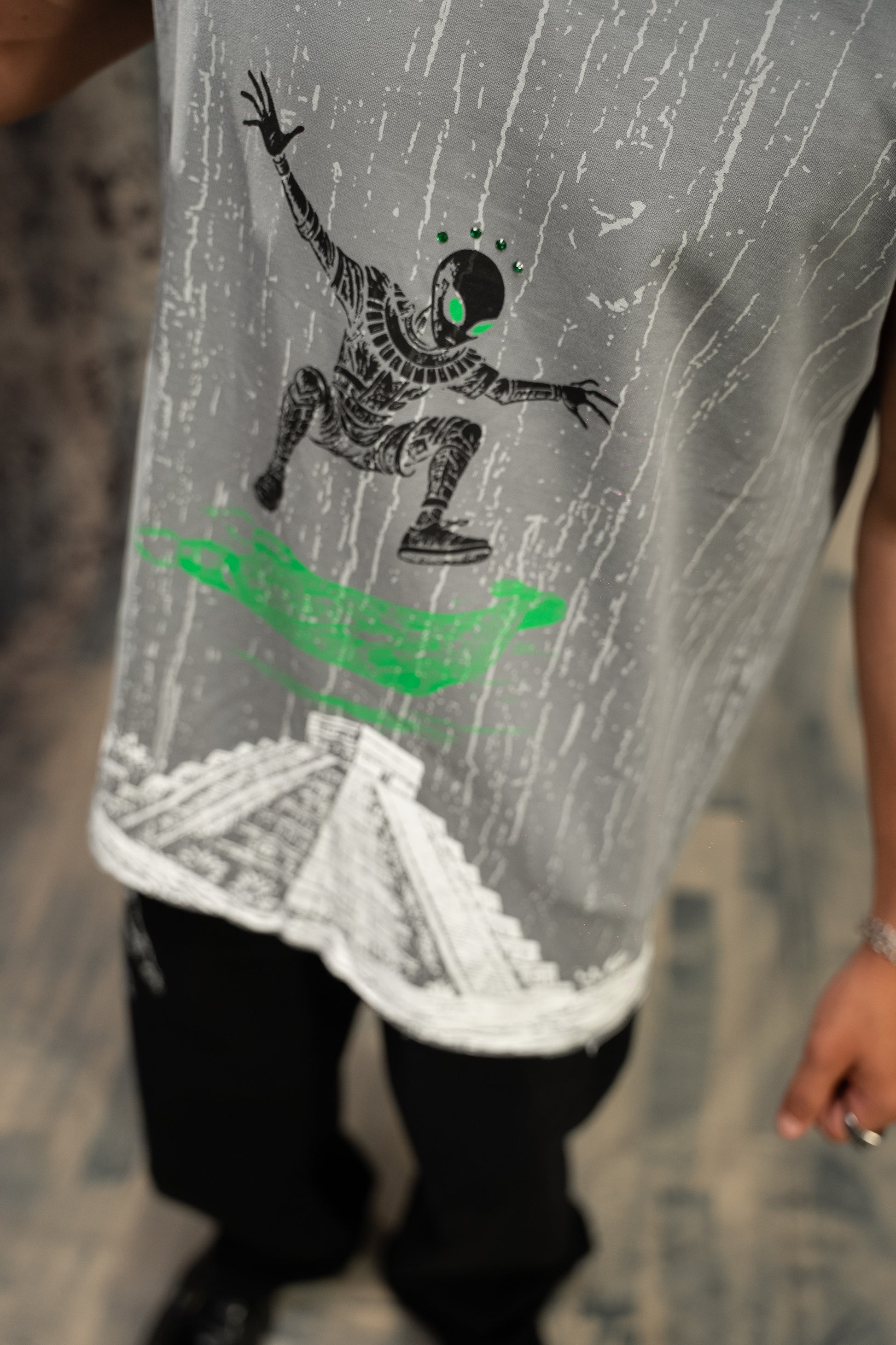 Gray sleeveless shirt with a graphic design of a person on a surfboard in green and black.