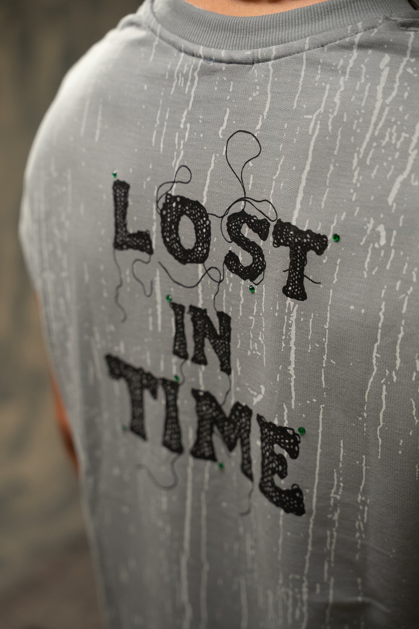 Gray sweatshirt with 'LOST IN TIME' text in black on a blurred background