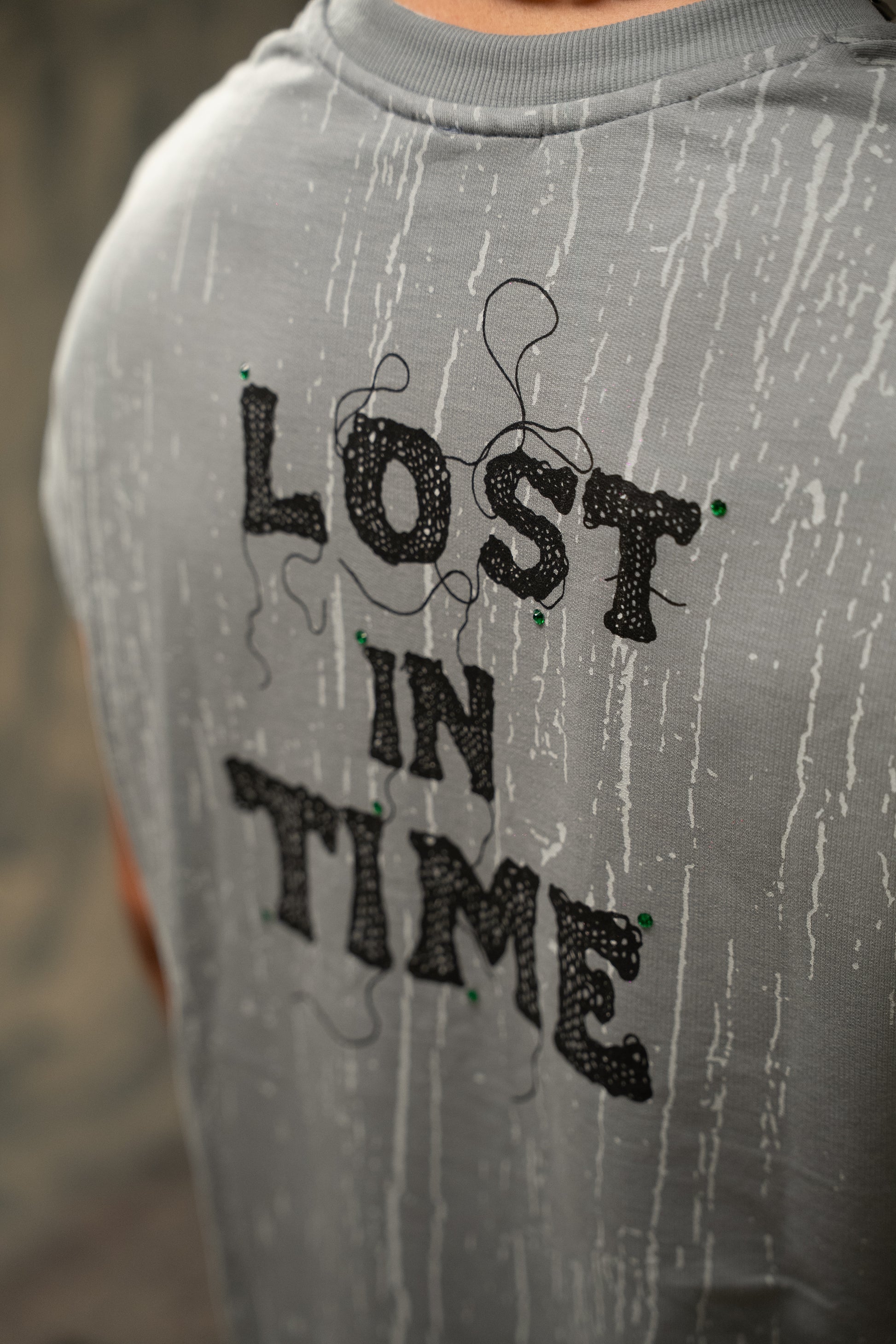 Gray sweatshirt with 'LOST IN TIME' text in black on a blurred background