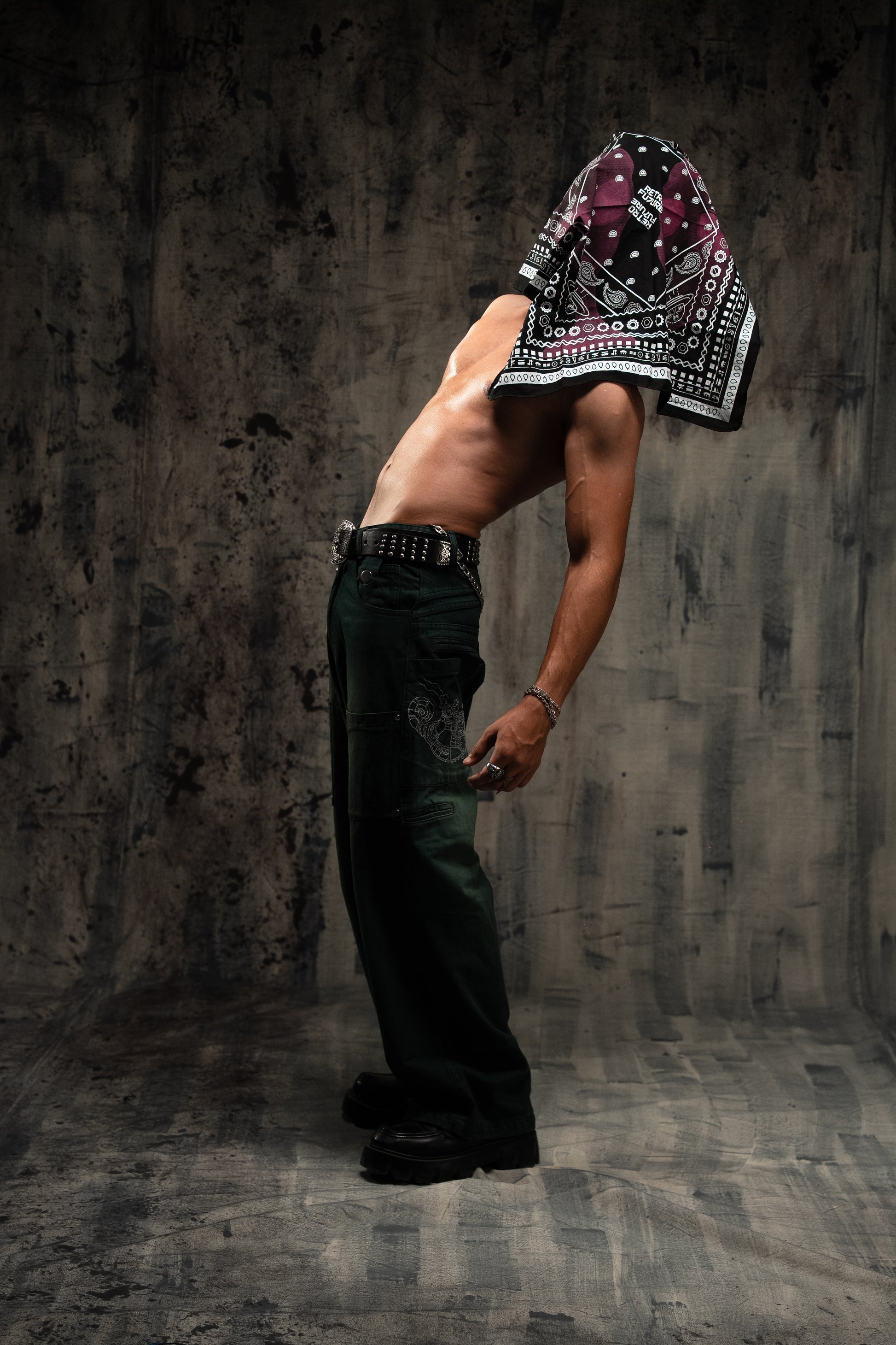 Person wearing a bandana over their head in a dark, textured room